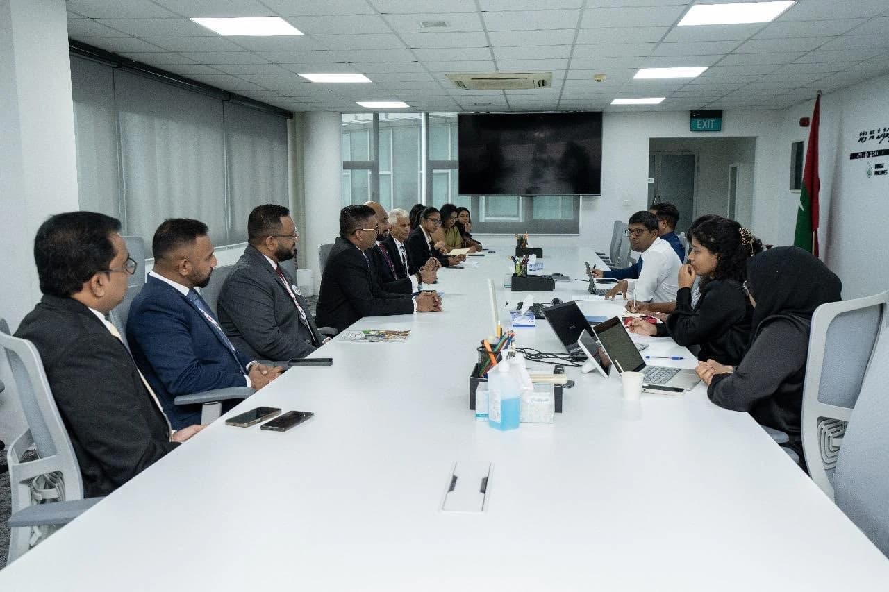 Business delegates in suits sit along one side of a long white conference table facing Economic Ministry officials, with a Maldivian flag in the corner.